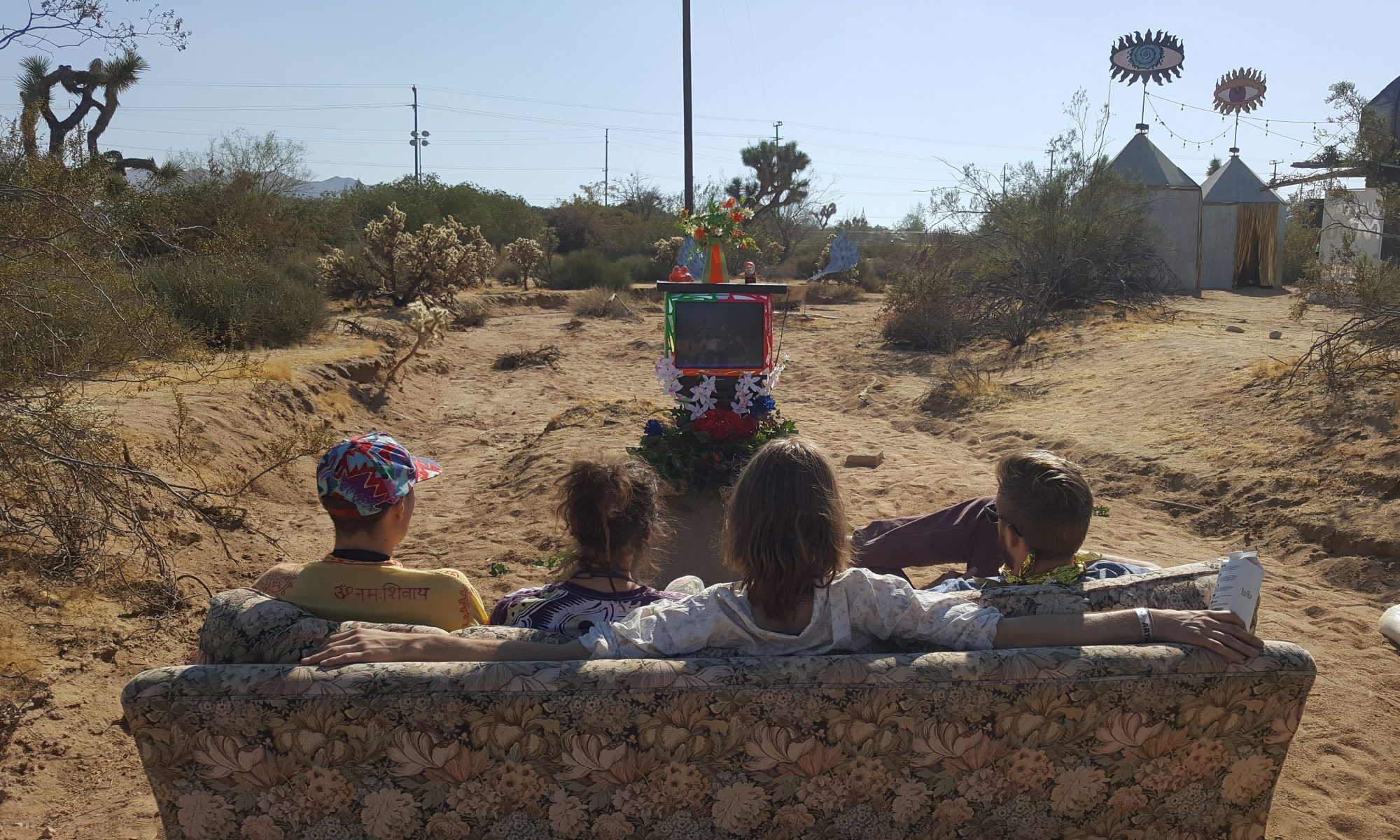 Four kids on a couch in the desert watching a decorated TV